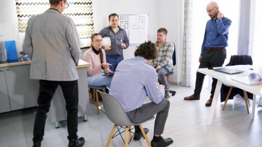 Bir grup insan aile ofisinin toplantı odasında bir masanın etrafında toplandı. Bir iş merkezi inşa etmenin aşamalarını tartışıyorlar. Sahne profesyonelce ve işbirliği içeriyor.