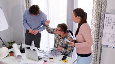 Şirketin mimari bölümünün başkanı astlarının çalışmalarından memnun değil. İnşaat şirketinin üç çalışanı projenin ayrıntılarını tartışıyor. Sahne ciddi ve odaklanmış.