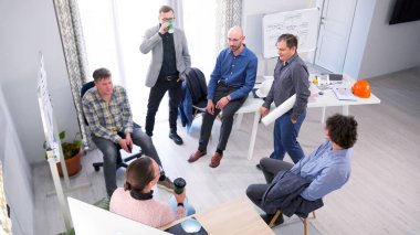 Bir grup erkek ve bir kadın önemli bir toplantıdan sonra bir konferans odasında öylesine sohbet ediyorlar. Bazı çalışanlar kahve içer. Olay yeri dostane, meslektaşlar sohbet etmek ve konuşmak için bir araya geldi..