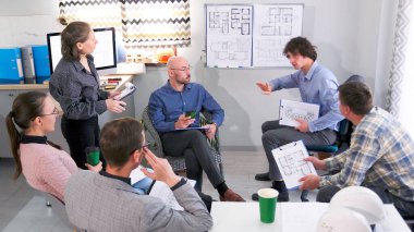 Bir grup insan çizimleri olan beyaz bir tahtanın etrafında toplandı. Beyin fırtınası seansı. Mühendisler ve tasarımcılar modern bir iş merkezi inşa etme projesinin fikir ve planlarını tartıştılar