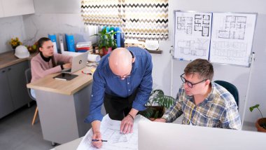 Mimarlık bölümünün başkanı astlarına bir emir verir. Mühendis projesini tasarımcıyla tartışıyor. Kadın bir sekreter erkeklerin arkasında oturup onlara bakar..