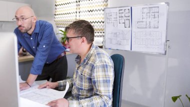 İki adam bir inşaat ofisinde çalışıyor. İki mimar bir kır evi projesini tartışıyorlar. İş adamı inşaat detaylarını koordine etmek için mühendis ile buluştu.