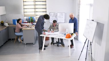 İşadamları, mimarla, inşaatın detayları ve projenin tahmini detaylarını koordine ederler. Bir grup ofis çalışanı bir konferans odasında birlikte çalışıyor. Takım çalışması ve odaklanma.