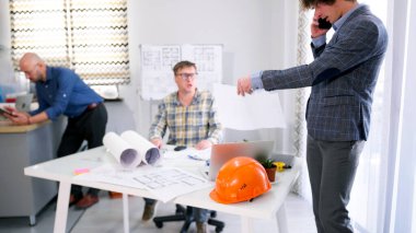 Mimarlık bürosunun ofisinde üç adam var. Biri cep telefonuyla konuşuyor. Bir mühendis akıllı bir ev projesi geliştiriyor. Proje bütçesinin tartışılması. Çalışma günleri.