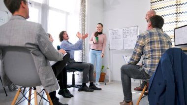 İnşaat şirketinin çalışanları bayan meslektaşlarını alkışlıyor. Bir grup insan çizimleri olan beyaz bir tahtanın etrafında toplandı. Mimari bir nesnenin sunumu