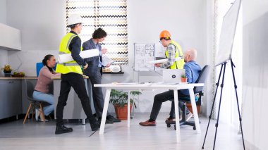 Yeşil yelekli iki işçi, yapılan işler hakkında inşaat şirketinin yönetimine rapor veriyor. Ustabaşı proje tahminini patronla koordine ediyor. Brifing ve takım çalışması.