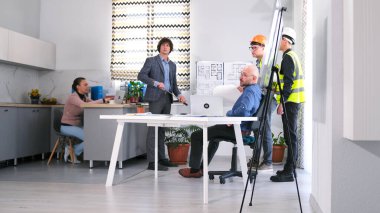 Mimarlık bürosundan bir grup insan konferans odasında bir toplantı için toplandı. Adamlar inşaat aşamalarını ve proje tahminlerini tartışıyor. Brifing ve takım çalışması.