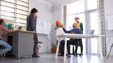İnşaatçılar, müteahhitler ve bir mimar akıllı bir ev inşa etmek için fikir ve kavramları tartışırlar. Toplantı odasında bir grup insan proje tahmini hakkında konuşuyor. Takım çalışması. Takım oluşturma