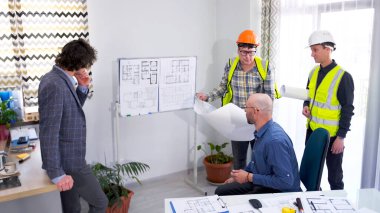 Müteahhitlerden oluşan bir ekip, bir mühendis ve bir mimar modern bir iş merkezi inşa etme planları ve çizimleri hakkında tartışıyorlar. Bir grup inşaat işçisi şirketin müdürüne rapor veriyor.