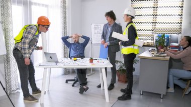 Proje bütçesinin onaylanması. İki inşaat işçisi ve bir yönetici konferans odasındaki baş mimarın masasında toplandılar. Proje planları ve çizimler hakkında. Takım çalışması..