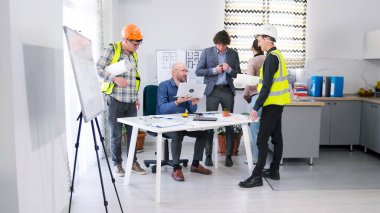 İnşaat şirketinin mutlu personeli inşaat planlarını tartışmak için konferans odasında toplandı. Mühendisler, mimarlar ve tasarımcılar projenin detaylarını koordine ederler..