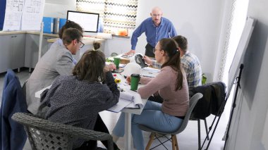 Patron bir pazarlama toplantısında kendini kaybetti. Öfkeli bir patron emrindekilere bağırır. Bir grup insan toplantı odasında bir masada oturuyorlar. Önlerinde bir adam duruyor ve talimatlar veriyor..