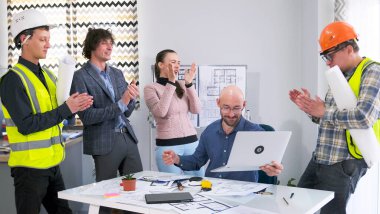 Bir mimarlık firması bir iş merkezi inşaatı ihalesini kazandı. Bir grup inşaatçı, bir tasarımcı, bir mühendis ve bir yönetici ellerini çırpıp gülümsüyor. Takım oluşturma