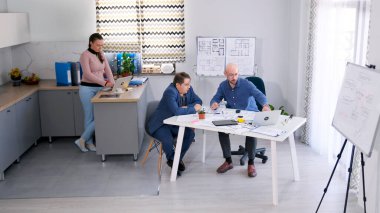 Müşteri ve baş mimarla inşaat şirketinin ofisinde buluşacağız. İki işadamı modern bir iş merkezi inşa etme planları ve çizimleri tartışıyorlar..