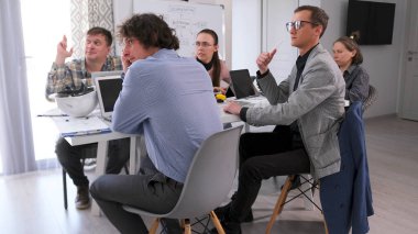 Bir grup yönetici dizüstü bilgisayarlarla bir masada oturuyor ve ortak bir proje üzerinde çalışıyorlar. Takım oluşturma, takım çalışması, beyin fırtınası. Genç uzmanlar projenin detaylarını tartıştılar