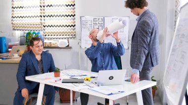 Mimarlık bürosunun çalışanları ofiste oyalanıyorlar. Üç adam bir proje üzerinde çalışıyor. Mühendisler proje için tahminlerde bulunuyor. Bir grup insan konferans odasında bir masada oturuyor.