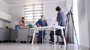 Toplantı ya da brifing. Üç adam bir konferans odasında bir inşaat projesini tartışıyorlar. Mimarlık Bürosu. Oda modern bir şekilde ışıklandırılmış ve dekore edilmiş..