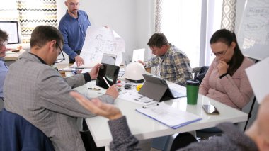 Planlar, baş mühendisin elinde. Mimar yeni bir iş merkezi inşaatı hakkında brifing için profesyonel ekibini topladı. Takım çalışması ve odaklanma