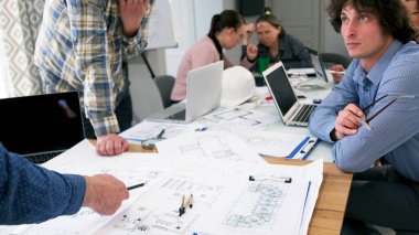 Mimarlık Bürosu 'nun ofisi. Çalışma günleri. Genç mimar patrona ve çizimlere dikkatle bakar. Bir grup insan kağıt ve dizüstü bilgisayarlarla bir masada oturuyor..