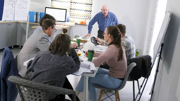 Patron bir pazarlama toplantısında kendini kaybetti. Öfkeli bir patron emrindekilere bağırır. Bir grup insan toplantı odasında bir masada oturuyorlar. Önlerinde bir adam duruyor ve talimatlar veriyor..