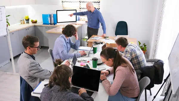 Şirketin çalışanları konferans odasında bir masada oturuyorlar. Erkek öğretim görevlisi bilgisayar ekranını işaret ediyor. Aile bürosunda sunum. Takım oluşturma. Takım çalışması. Beyin fırtınası.