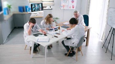 Beyaz önlüklü bir grup araştırmacı hastanenin sıcak aile ofisinde bir masada oturuyorlar. Biyohack kliniğinde bir toplantı. Doktorlar yeni bir ilaç geliştiriyor.