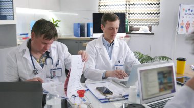 Bir grup araştırmacı konferans odasında dizüstü bilgisayarlar üzerinde çalışıyor. Doktorlar tüm hastalıklar için bir tedavi geliştiriyorlar. Beyaz önlüklü adamlar tıbbi bir proje üzerinde çalışıyorlar.