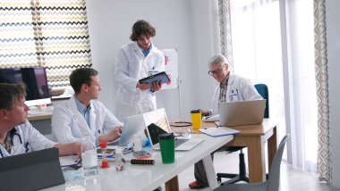 Bir grup doktor konferans odasındaki masanın etrafında toplandı. Davayı hastayla tartıştılar ve bir aşı geliştirdiler. Sahne ciddi ve odaklanmış. İş yerindeki araştırma personeli