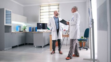 Hastanenin müdürü kliniğin rahat konferans odasında baş cerrahla konuşuyor. İki doktor ayakta tıp ve bilim haberlerini tartışıyor. Sahne profesyonel ve ciddi.