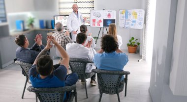 Başarılı bir doktor bilim ve tıp alanındaki yeni araştırmasının sunumunu yaptı. İzleyicilerden bir grup insan onu alkışlıyor. Stajyerlerin sağlık ocağında verdiği bir ders..