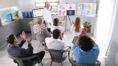 Seyirci tıp konulu bir konferansta alkışlıyor. Bir grup insan, bir adamın sunum yaptığı klinikte ellerini çırpıyor. Seyirci, doktorun performansı karşısında büyülendi.