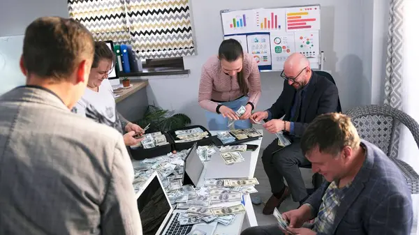 Bir grup insan, sıcak bir aile ofisinde para dolu bir masada oturuyor. Şirketin çalışanları nakit para sayıyor. İhaleyi kazanmak..