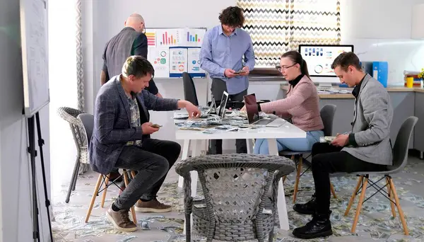 Bir kaç erkek ve bir kadın dolar dolu bir ofiste oturuyorlar. Ofis çalışanlarından oluşan bir ekip masa başında oturur ve bugünkü kârı sayar. Finansörler iş başında