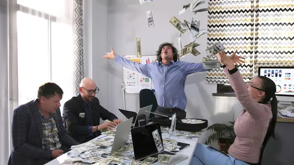 Bir adam havaya para atıyor ve diğer insanlar ona bakıyor. Eylem, bir grup insanın bir masada oturduğu bir konferans odasında gerçekleşiyor..