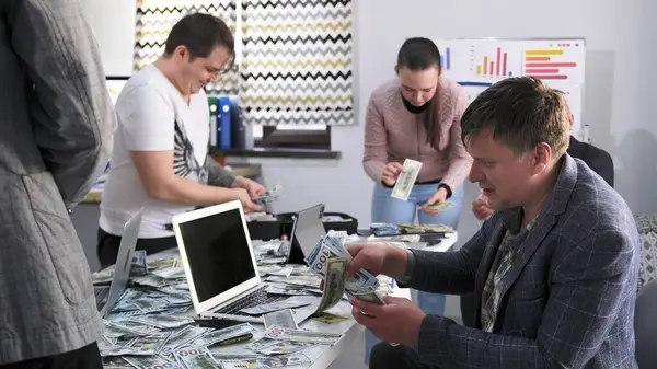 Adam ve meslektaşları parayı sayıyor. Bir grup arkadaş piyangoda büyük miktarda para kazandı. Sahne heyecan ve heyecanla dolu.