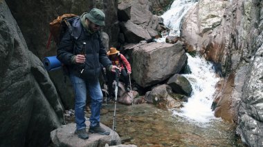 İki yürüyüşçü şelaleden nehri geçiyor. Elinde bir şişe bira ve turist sırt çantasıyla bir adam bir arkadaşıyla birlikte ülkesinin güzel yerlerine seyahat ediyor..