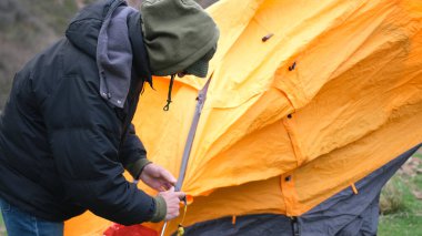 Adam çadırın kemerlerini tamir ediyor. Eğitmen turistlere kamp gezisinde nasıl çadır kurulacağını öğretiyor. Yalnız bir yolcu gece için durdu ve bir çadır kurdu..