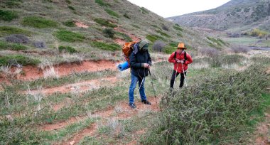 İki yorgun yolcu haritayı kontrol etmek için yolda durdu. Rehber telefonunu çıkardı ve izleri kontrol etti. Dağlarda yürüyen gezginler