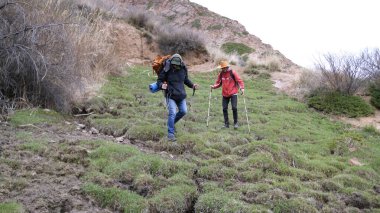 Turistler zorlu bir tırmanıştan sonra geçitten inerler. İki arkadaş sırt çantaları ve yürüyüş direkleri ile yürüyüş yapıyorlar. Rehber ve yardımcısı yeni bölgeyi keşfediyor.
