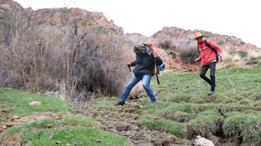 Öğrenciler yağmurdan sonra çamurlu bir dağ yolunda yürürler. Kirlenmemek için tümseklerin üzerinden dikkatle geçerler. Seyahat, yürüyüş ve özgürlük.
