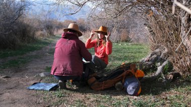 Gezinti. Toprak bir yolun kenarında bir ağacın altında iki kişi oturuyor. Kız arkadaşlar doğru yere gitmek için haritaya bakarlar. Güneşli bir günde yürüyüş. Seyahat ve turizm