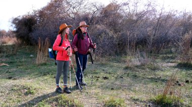 İki güzel genç kadın hafta sonunu aktif olarak geçiriyorlar. Yürüyüşçüler sırt çantaları ve şapkalarla sahada yürürler. Özgürlük, seyahat ve macera.