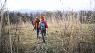 Bir grup turist otlarla kaplı bir arazide yürüyorlar. Gezginler dağlara doğru gidiyor. Hafta sonu kamp gezisi. Gezginler aktif olarak zaman geçirirler