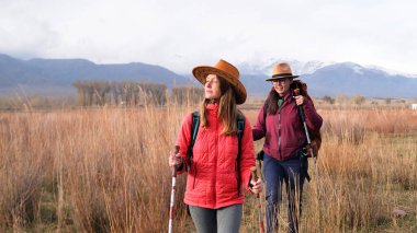 Barış, sükunet ve doğa ile birlik. Hafta sonu kamp gezisi. İnsan sinir sisteminin yeniden başlatılması. İki kadın büyümüş bir tarlada yürüyor. Dağlar arkada görünür.