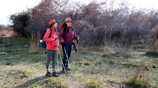 İki güzel genç kadın hafta sonunu aktif olarak geçiriyorlar. Yürüyüşçüler sırt çantaları ve şapkalarla sahada yürürler. Özgürlük, seyahat ve macera.