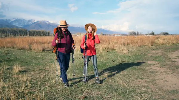 İki gezgin, gün batımında kar kaplı dağların yakınındaki bir tarlada temiz havada yürümenin tadını çıkarıyorlar. Lezbiyen bir çift yürüyüş yapıyor. Aktif hafta sonları. Harika bir tatil.