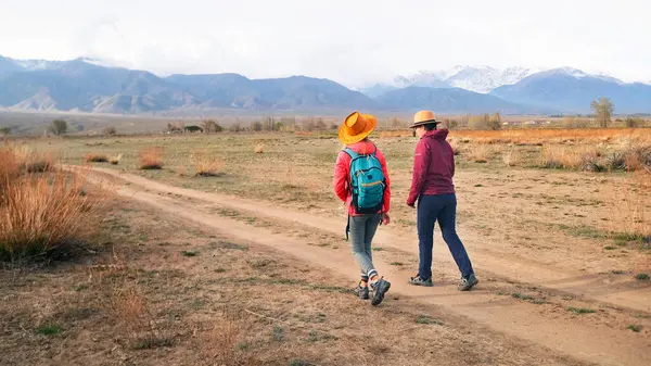Issız bir bölgede toprak bir yolda yürüyen iki kişi var. Sahne huzurlu ve sessiz. Kadınlar yürüyüşün tadını çıkarıyorlar. Gezinti ve yürüyüş. Günbatımından önceki tipik bir yürüyüş