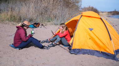 İki kız kardeş sahilde bir çadırda oturuyorlar. Gezginler telefonlarıyla sohbet ederler. Hafta sonları dışarıda. Gölün kıyısındaki sahilde kamp yapmak. Gezinti ve yürüyüş