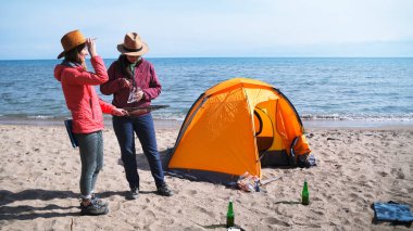 Turistler bir çadırla sahilde dinlenirler. İki genç bayan gezgin bir kamp ateşinin üzerinde ızgara sosis yemek için deniz kenarında durdu. Romantik randevu