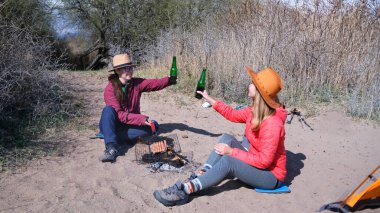 İki yolcu sahilde bira şişelerini tokuşturuyor. İki kadın sahilde kamp ateşinin yanında oturmuş sosis kızartıyorlar. Öğrenciler bira içip dışarıda eğleniyorlar.